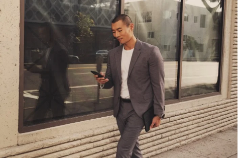 Young professional walking down the street looking at phone